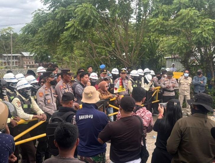 Barisan aparat keamanan dan warga dalam pertemuan di luar ruang terbuka.