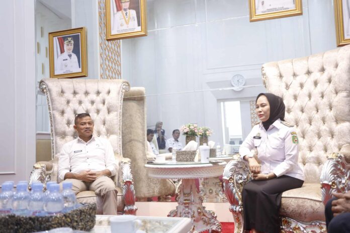 Perwakilan resmi di ruangan kantor dengan dekorasi mewah dan foto pejabat di dinding.