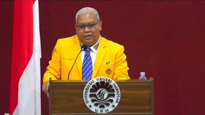 Pemeran pria berbaju kuning sedang berbicara di depan podium di Universitas Negeri Malang.