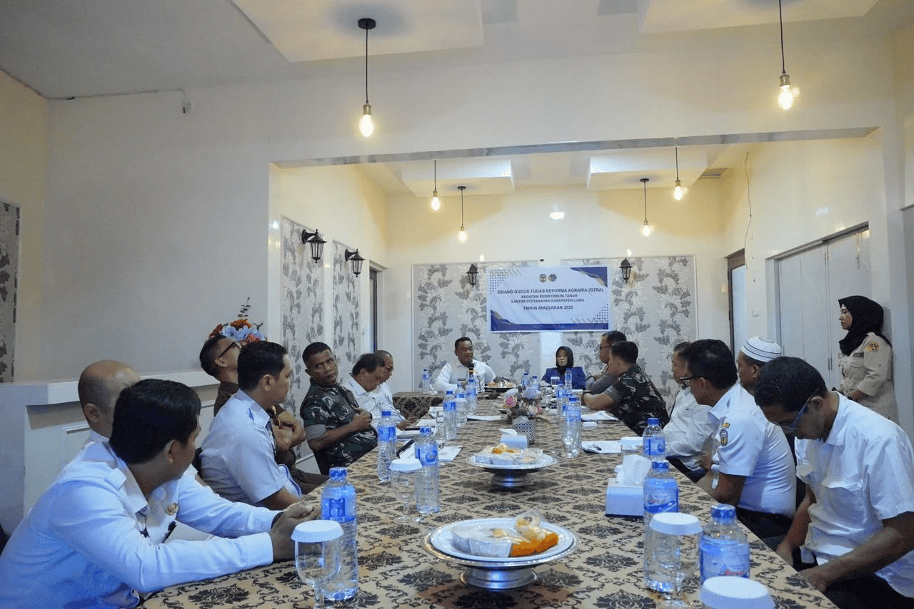 Pertemuan resmi di ruang rapat kantor pemerintah dengan pejabat dan staf berseragam, diskusi tata kelola agraria dan pembangunan daerah.